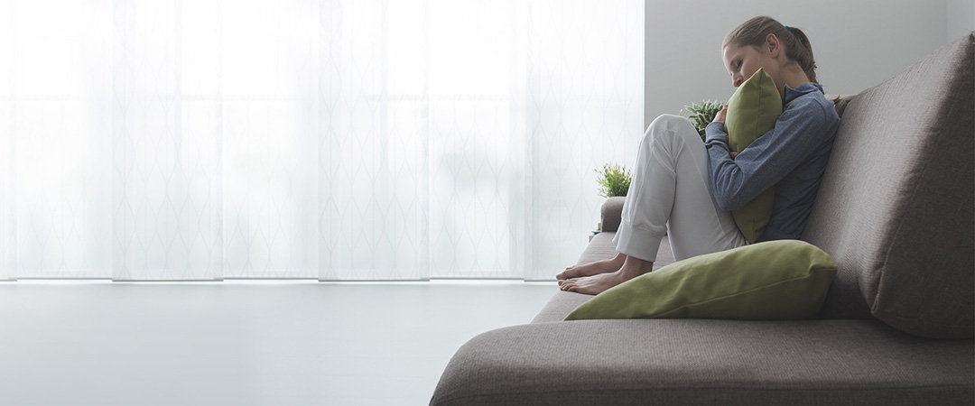 Woman hugging a pillow curled up on a couch.