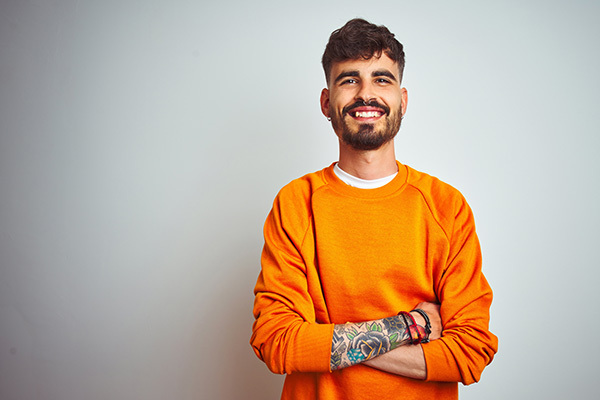 Smiling man crossing his tattoed arms.